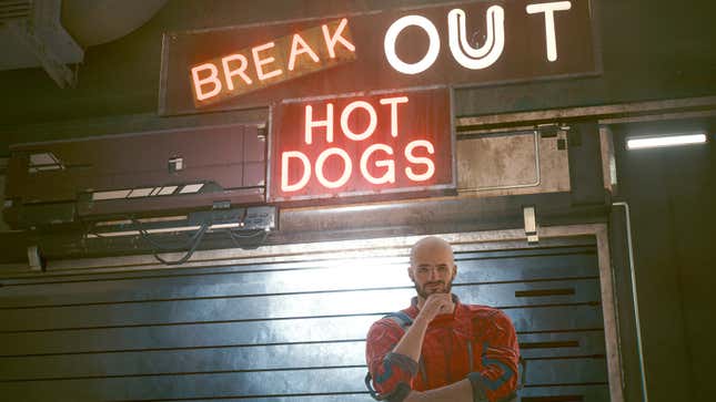 V stands in front of the Break Out Hot Dogs joint with the door shut behind him.