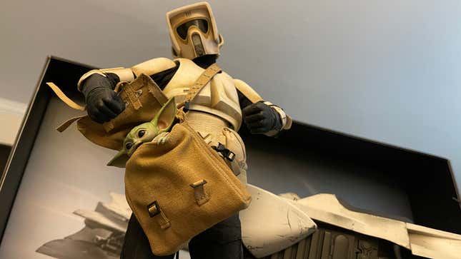 A toy Imperial Scout Trooper prepares to punch a toy Baby Yoda stuffed in a sack. 