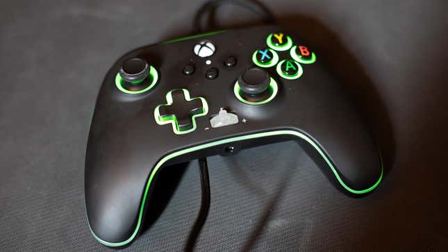 A green LED-lit Power-A controller sits on a rubber mat.