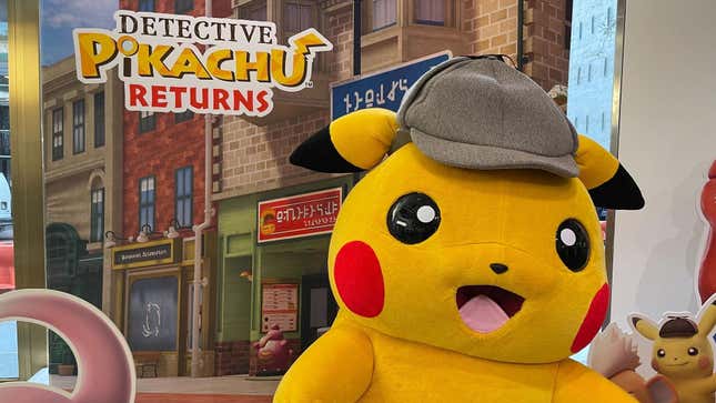 A Detective Pikachu mascot is shown in front of a display marketing Detective Pikachu Returns.