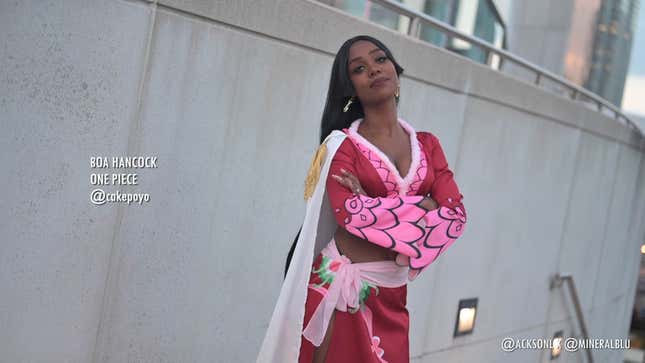 A cosplayer dressed as One Piece's Boa Hancock stands with arms crossed over their chest. 